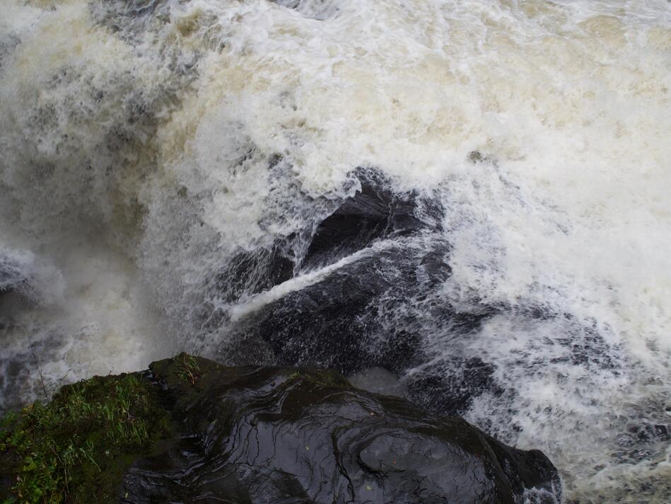 White spray splashing over a dark brown rock.